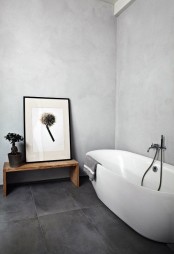 a minimalist bathroom with light grey walls, a graphite grey floor, white appliances and statement artworks