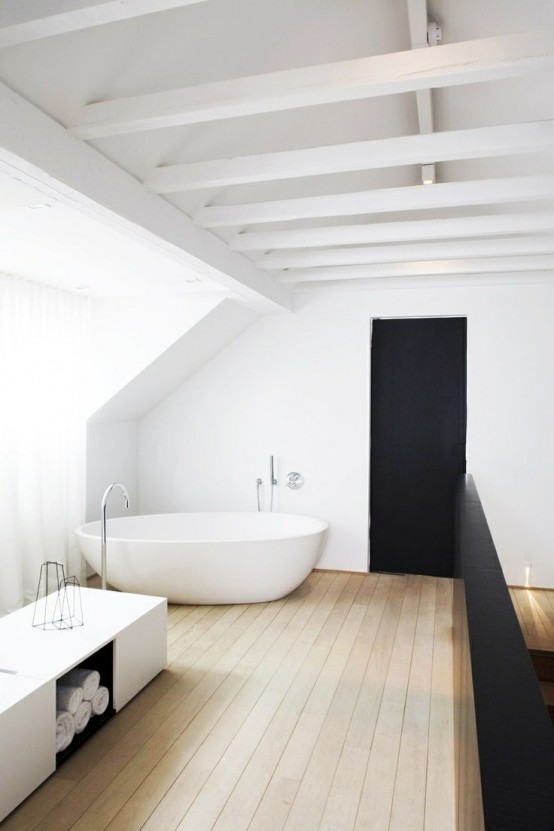 a contrasting minimalist bathroom with a white ceiling with beams, a white bathtub, a white bench with storage and a wooden floor
