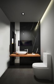 a refined minimalist powder room with a black marble wall, a floating vanity, white walls, white appliances and built-in lights