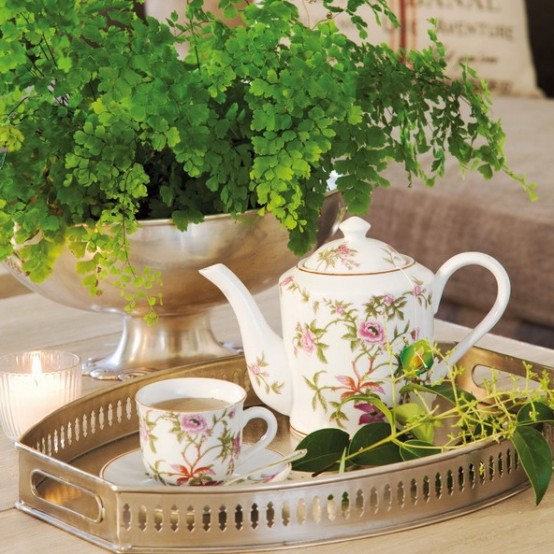 a metal planter with lots of greenery and a metal tray with greenery and floral teaware