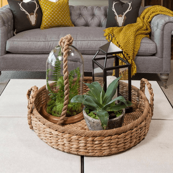 a basket tray with a terrarium, a candle lantern and a potted plant for a boho chic feel