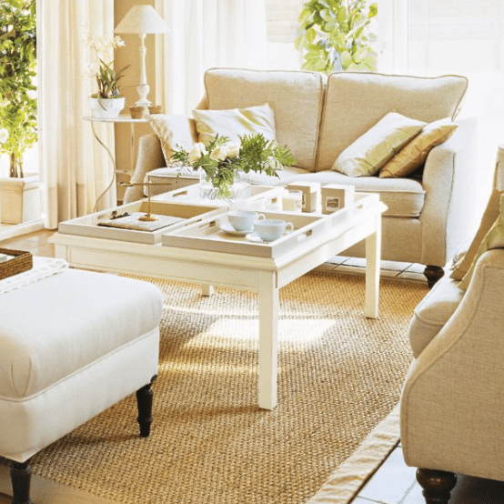 a white coffee table with trays, coffee cups, greenery and blooms and some candles