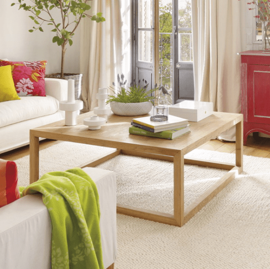 a contemporary coffee table with some books, candles and potted blooms for a clean and airy feeling