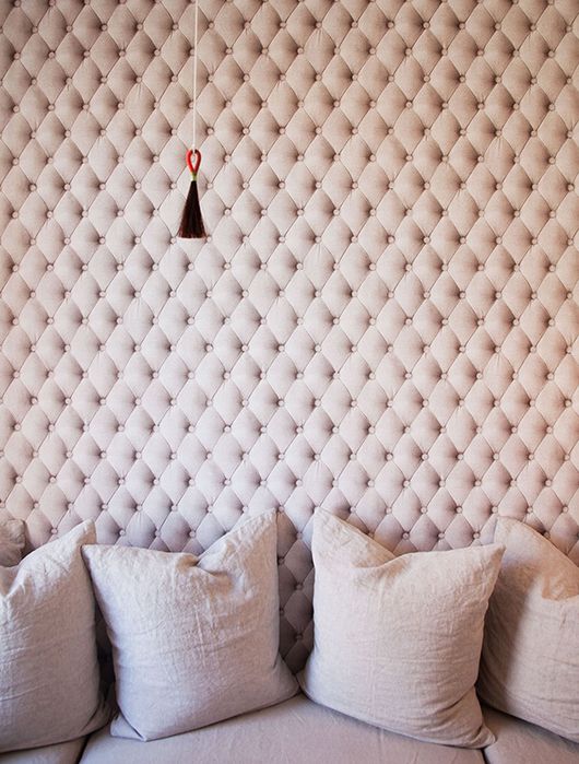 an upholstered tufted wall in blush isn't only a catchy decor feature but also a cool soundproofing idea