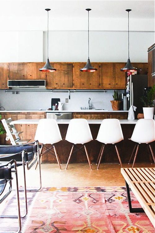 a rich-stained and white mid-century modern kitchen, white chairs and pendant lamps