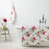 a cute white bathroom with a brick wall, a modern bathtub, colorful textiles and a small stool