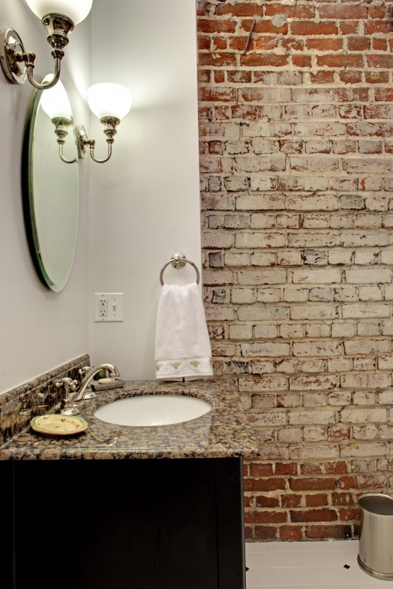 a vintage powder room with whitewashed brick walls, a stone countertop vanity, wall lamps, a round mirror looks catchy