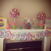 a bright Easter mantel with colorful paper topiaries, bunny figurines and a colorful bunting