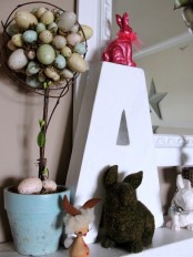 a pastel speckled egg Easter topiary, bunny figurines and a monogram is a simple mantel decor idea