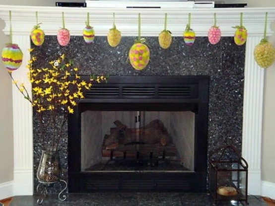 colorful paper Easter eggs hanging on the mantel and blooming branches in vases