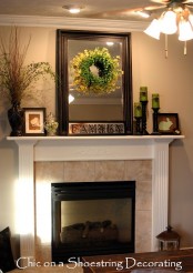 a spring Easter mantel with green candles, a jar with green eggs, some signs, blooming branches in vases