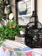 vintage Easter mantel decor with a cage, some baskets and fake birds, potted greenery and a wreath