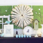 a blue Easter mantel with fake eggs and birds, some bunnies and branches with fake flowers