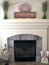 colorful faux eggs on the mantel and ina  wreath, an Easter sign and fake greenery with butterflies