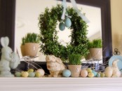 pastel eggs, bunny figurines, potted grass and a greenery wreath with an egg