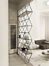 a geometric shelving unit separating the spaces, the living room and entryway, is a stylish idea for a modern space, it’s airy and cool