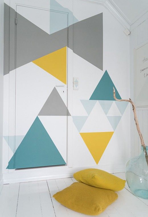 a geometric accent wall and door and mustard pillows that match the colors of the wall