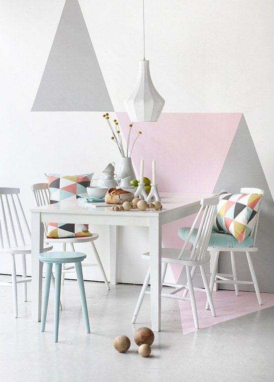 an airy Scandinavian dining space with a pastel geometric accent wall, a white table and vintage chairs, a mint stool and printed geometric pillows