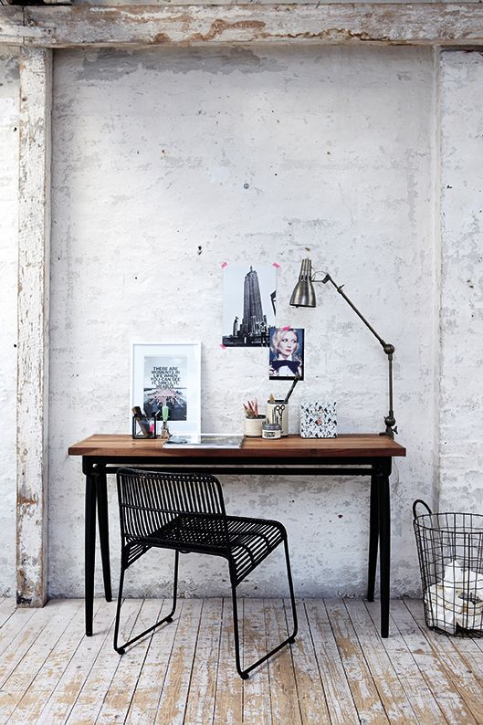 a shabby chic to industrial home office with white shabby walls, an industrial desk of wood and metal, a metal table lamp and a black metal chair