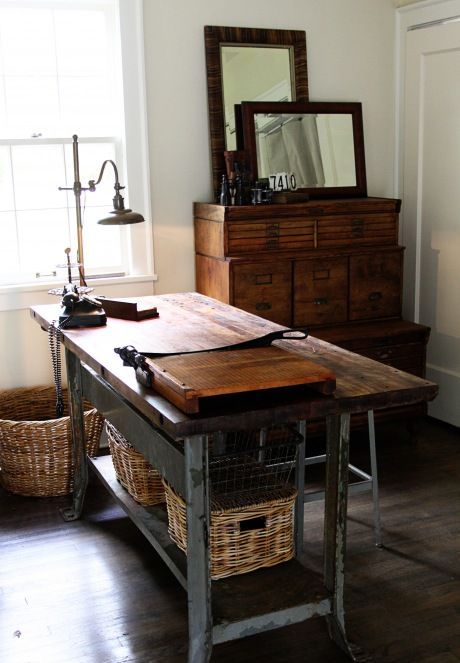 a vintage industrial and rustic home office with vintage stained cabinets for storage, an industrial desk of stained wood and metal, a metal table lamp and a basket