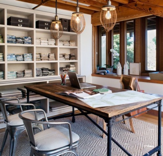 a modern home office with a neutral storage unit, a wood and pipe industrial desk, pendant lamps and metal chairs with upholstery