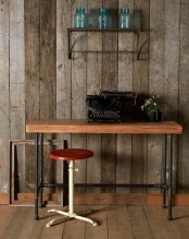 a chic industrial home office with a reclaimed wooden wall, a metal shelf for storage, an industrial desk of wood and metal, a matching stool and a vintage typewriter