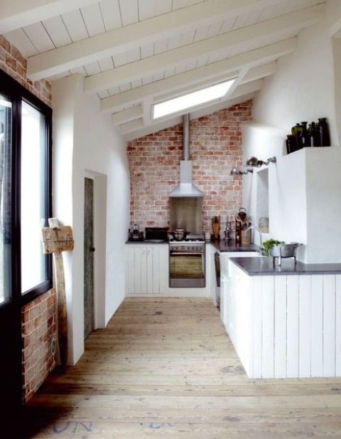 a red brick wall and white wooden cabinets bring in texture and contrast with each other