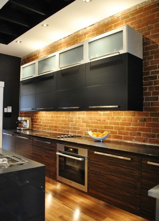 a red brick wall adds texture and color to the space and contrasts the sleek cabinets