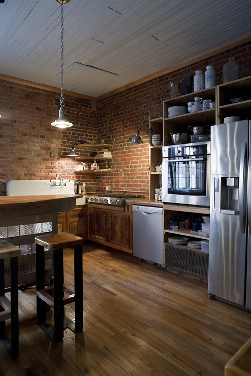 red brick walls match the rich stained wood and add texture and interest to the kitchen