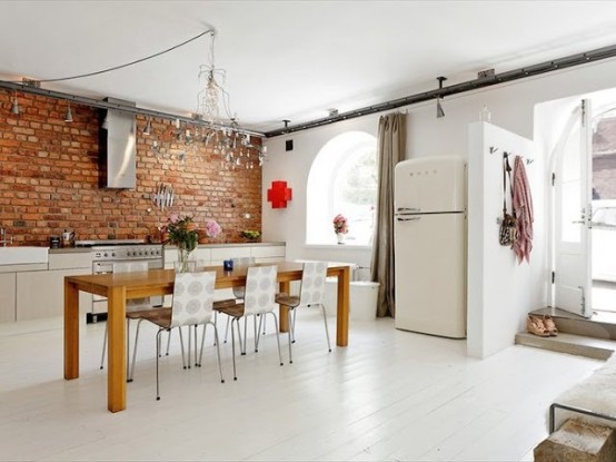 a bright white kitchen is spruced up with a red brick wall that adds interest to the space and makes it more color-filled
