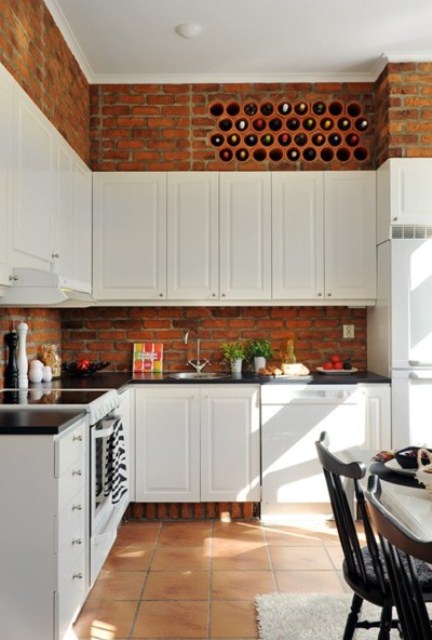 vintage white cabinets and red bricks contrast with each other and add texture to the kitchen