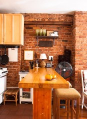 a red brick wall and light stained wooden furniture make up a cozy warm colored dining nook