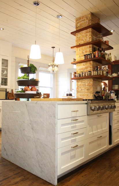 a brick pillar with wooden shelves is a catchy decor element that adds texture and storage space to the kitchen