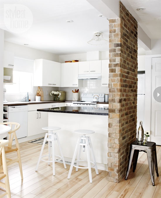 a red brick pillar separates the kitchen from the next space adding interest and texture to both