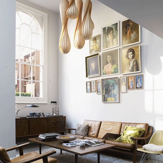 a neutral mid-century living room with a vintage gallery wall, leather and dark stained wooden furniture and an arched window