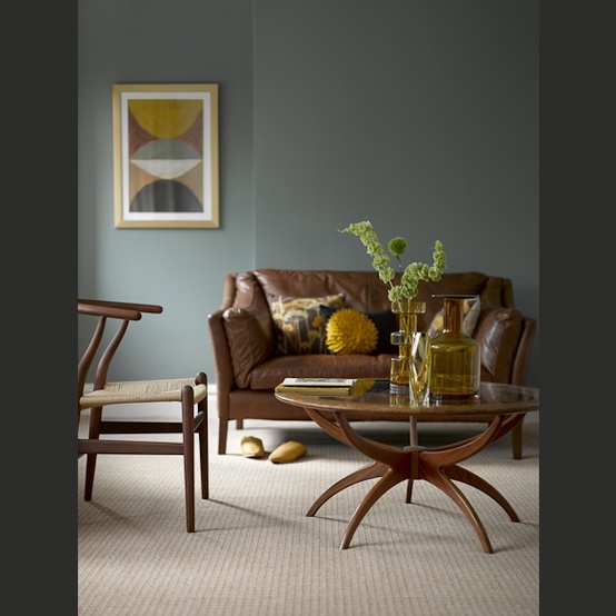 a mid-century modern living room with slate grey walls, dark stained furniture and a neutral floor