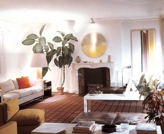 an airy living room with white furniture, a faux fireplace, potted greenery and leather touches