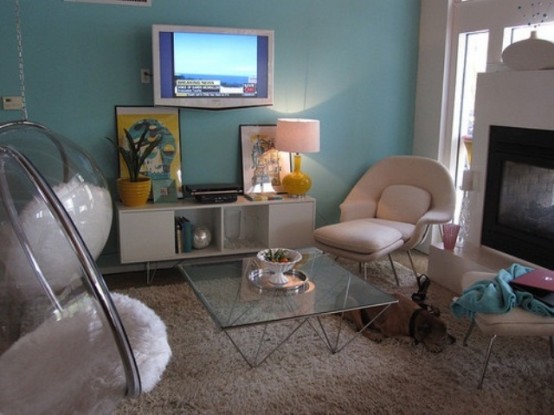 an eclectic living room with blue walls and creamy furniture, a fireplace, hanging round chairs