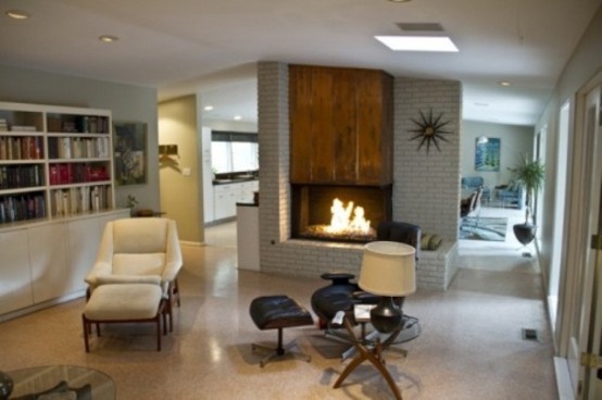 an airy living room with a built-in fireplace, creamy and black furniture, a built-in bookcase and elegant decor