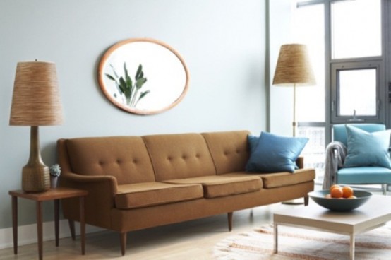 a welcoming living room done with blue and brown furniture and pillows, lamps and a mirror