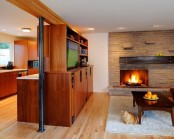 a welcoming living room with a faux stone wall, a built-in fireplace, a stained wooden furniture unit and fluffy rugs