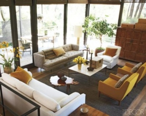 a mid-century modern living room with grey, yellow and creamy furniture, potted greenery and blooms and a stained wooden cabinet