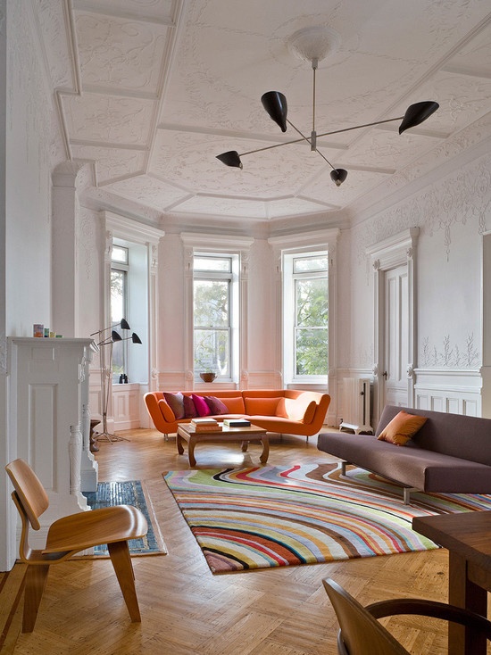 a white vintage-inspired living room with stucco on the walls and ceiling, bright furniture, a printed rug, a chic fireplace