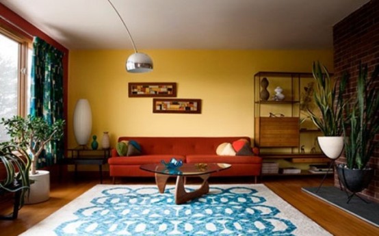 a colorful mid-century modern living room with a yellow and brick wall, printed textiles and potted plants