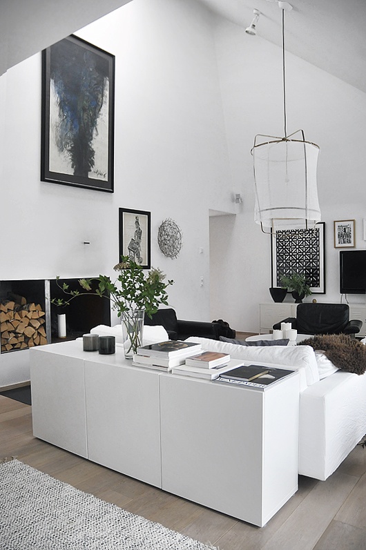 a monochromatic Nordic living room with black and white furniture, pendant lamps and firewood storage for more coziness