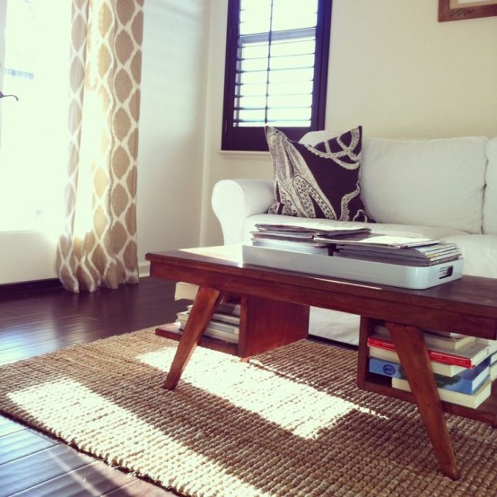 a rich-stained coffee table with tall legs and open storage compartments for books under the tabletop is functional