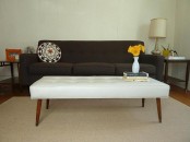a mid-century modern coffee table or bench upholstered with white leather and with rich-stained tapered legs is a cool solution