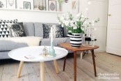 a duo of Scandinavian coffee tables – a small round white one and a triangle-shaped rich-stained coffee table