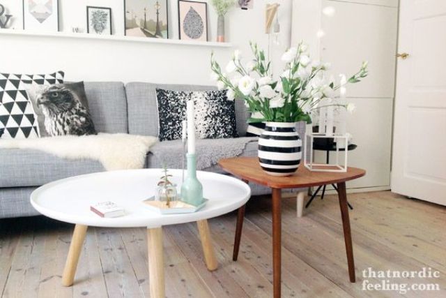 a duo of Scandinavian coffee tables   a small round white one and a triangle shaped rich stained coffee table
