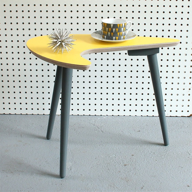a Scandinavian mid century modern coffee table on tall grey legs and with a curved and creatively shaped yellow countertop will make a statement with both its color and shape